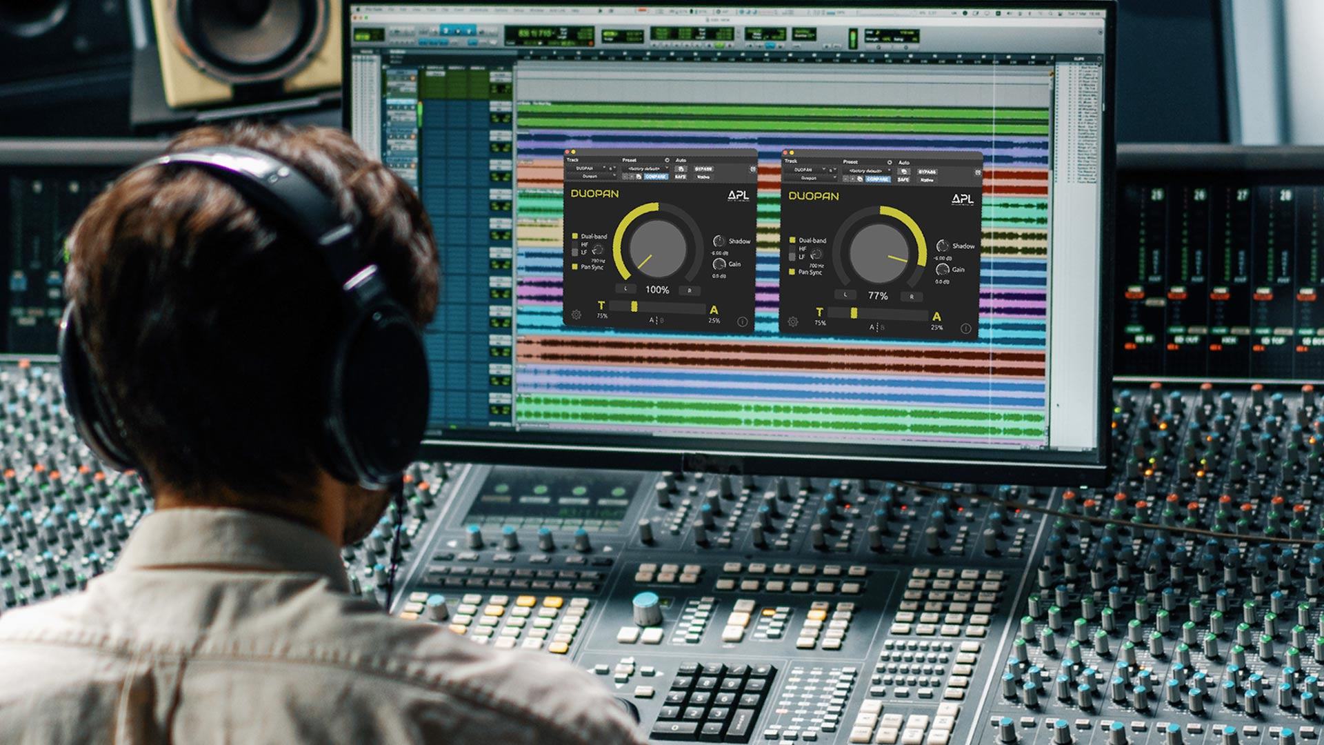 A sound engineer sitting in front of a mixing desk in a music studio