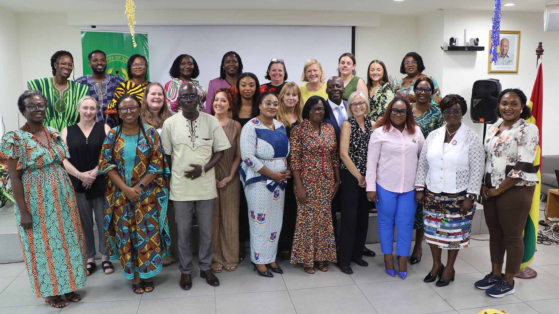 A group of staff and students from Huddersfield and Ghana stand in two rows looking at the camera