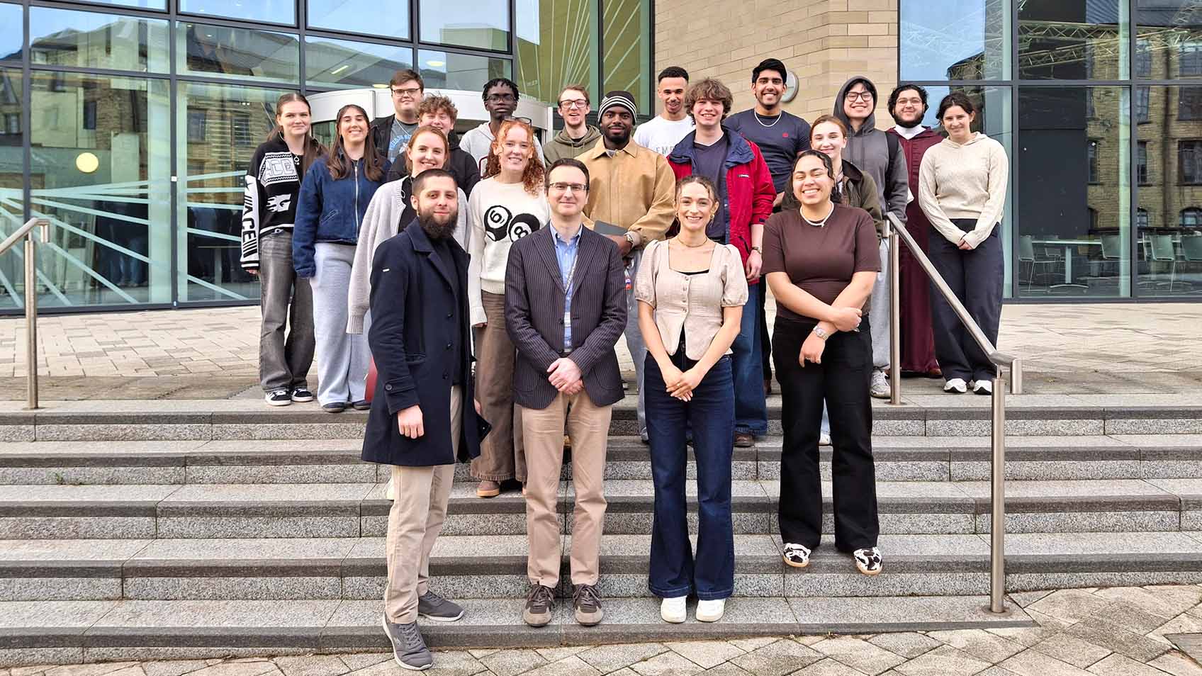 Sgtudents stand on steps and smile at the camera at the Barbara Hepworth Building