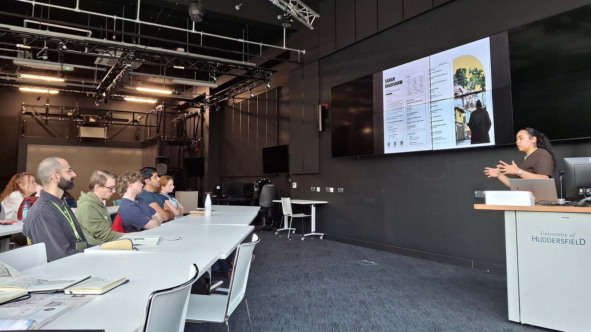 Sarah Bradshaw talks to students in front of a screen