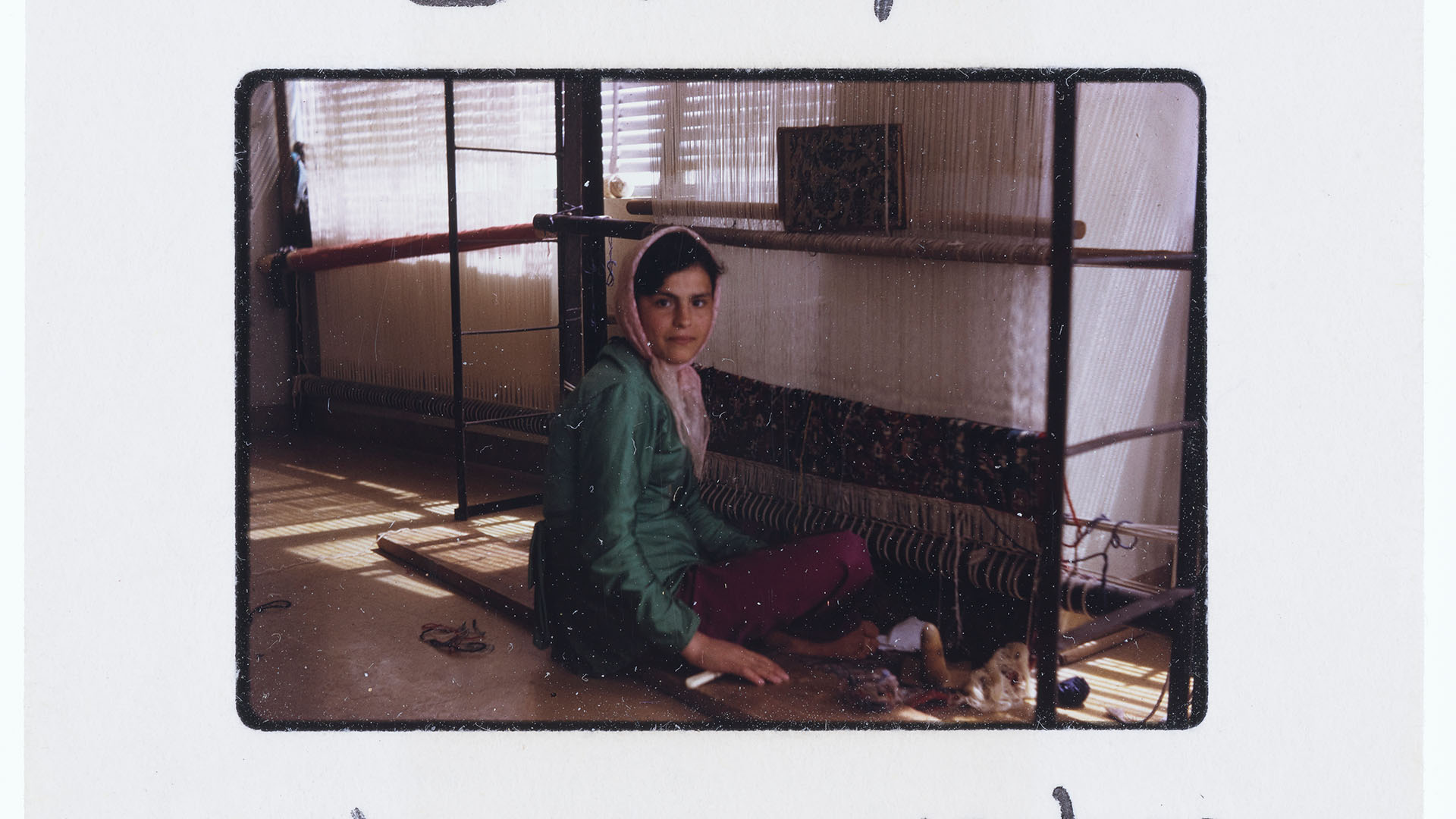 A slide photo of a girl in a refugee centre working on textiles