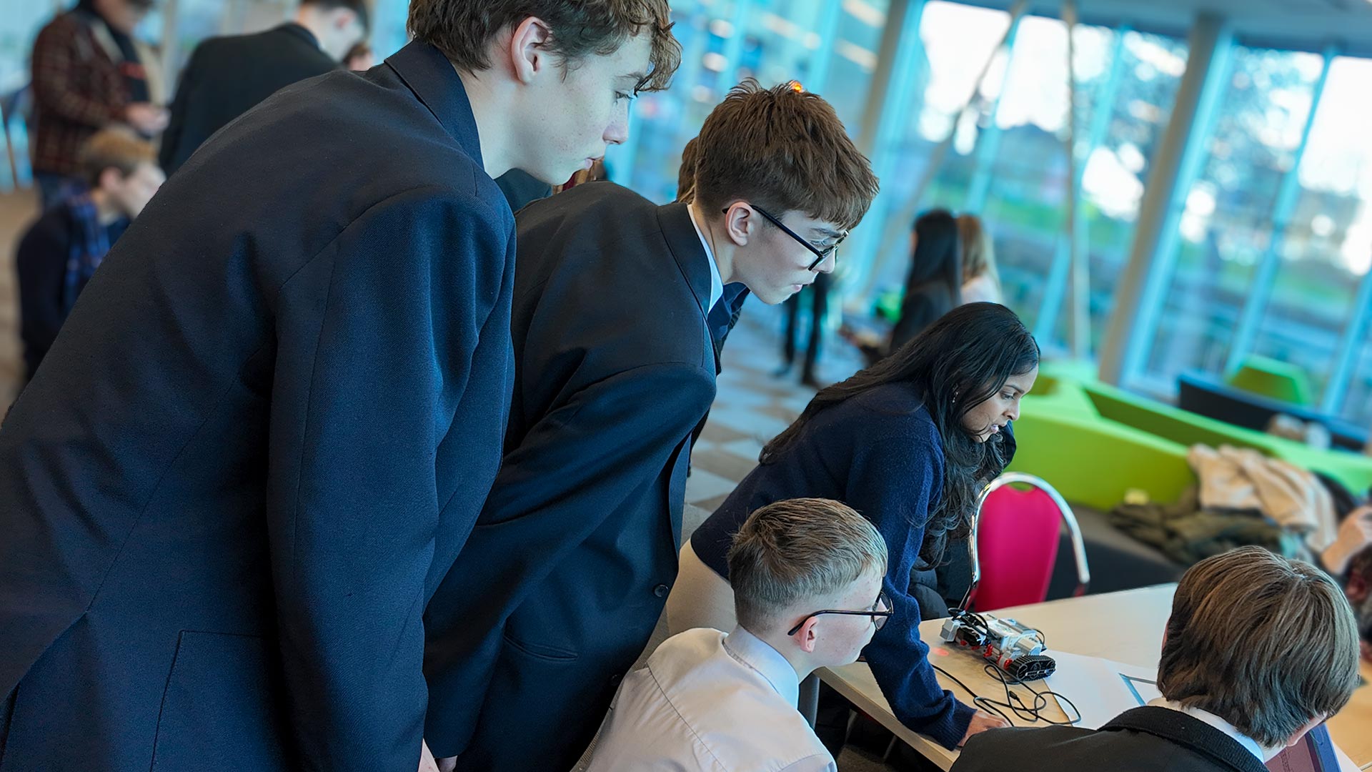 A group of students gathered around a table with a Lego robot