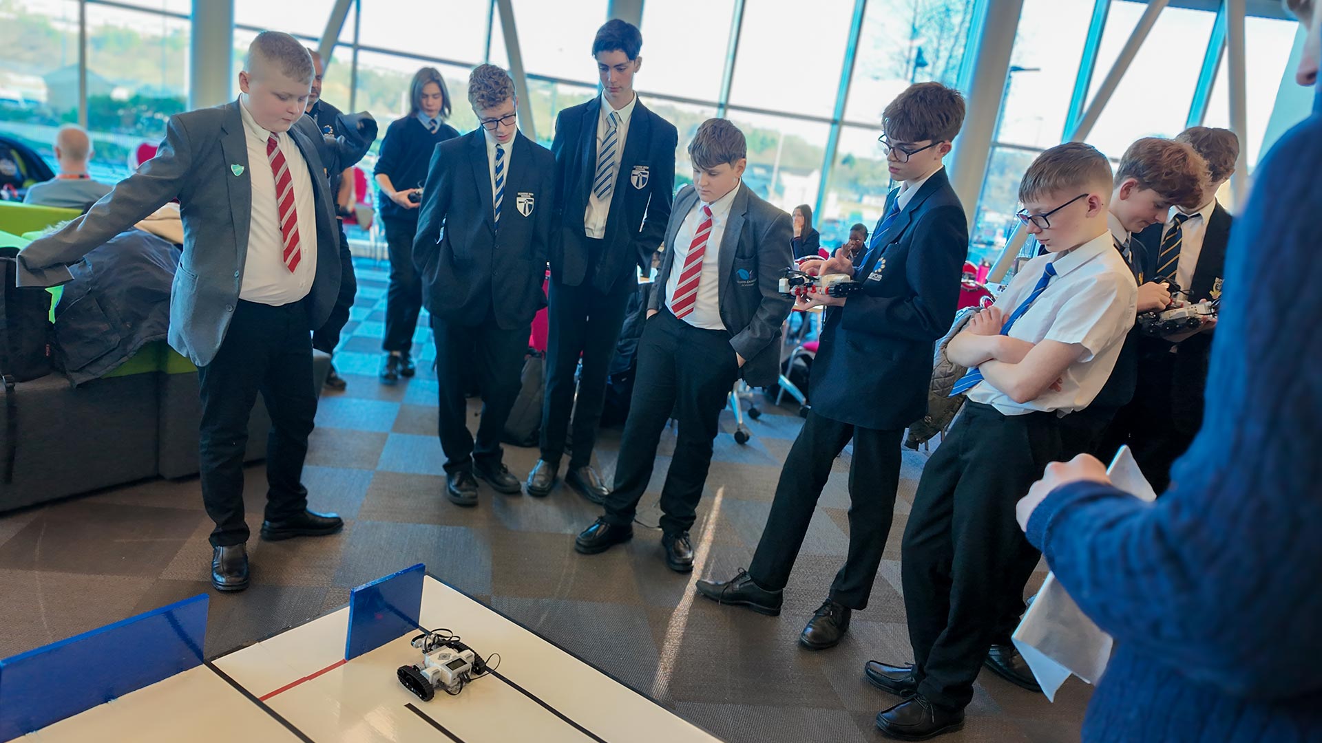 Students gathered around a robot navigating a 3D maze