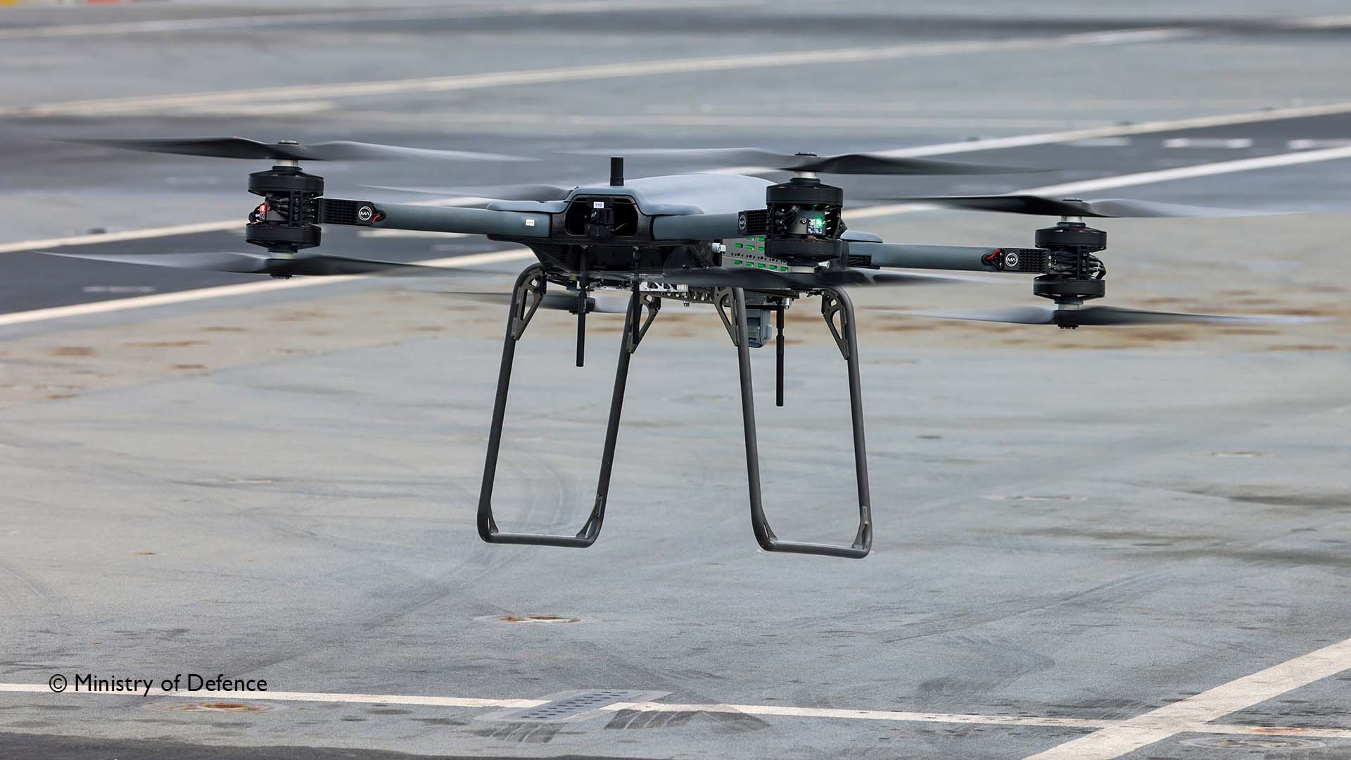 A drone hovers above the deck of an aircraft carrier
