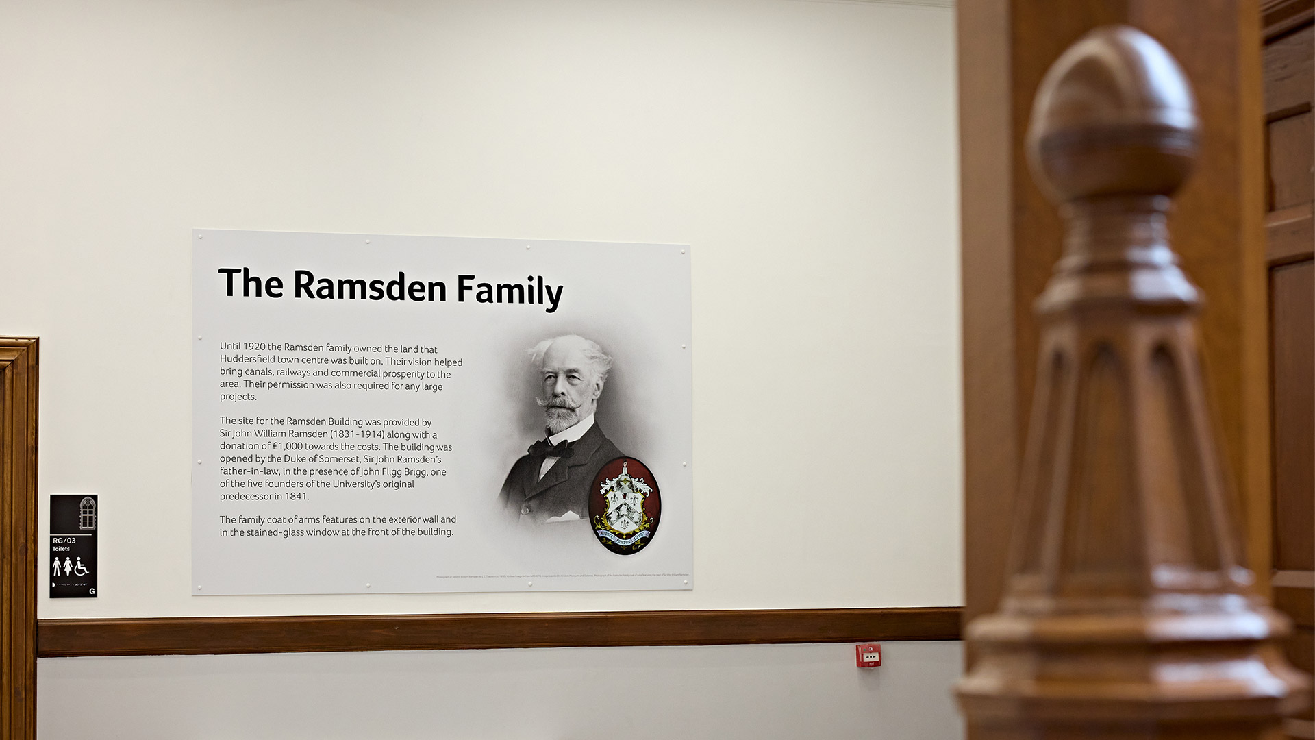 Interpretive display about the Ramsden family mounted inside a historic building, with portrait, heritage information panel and original wooden architectural features visible.