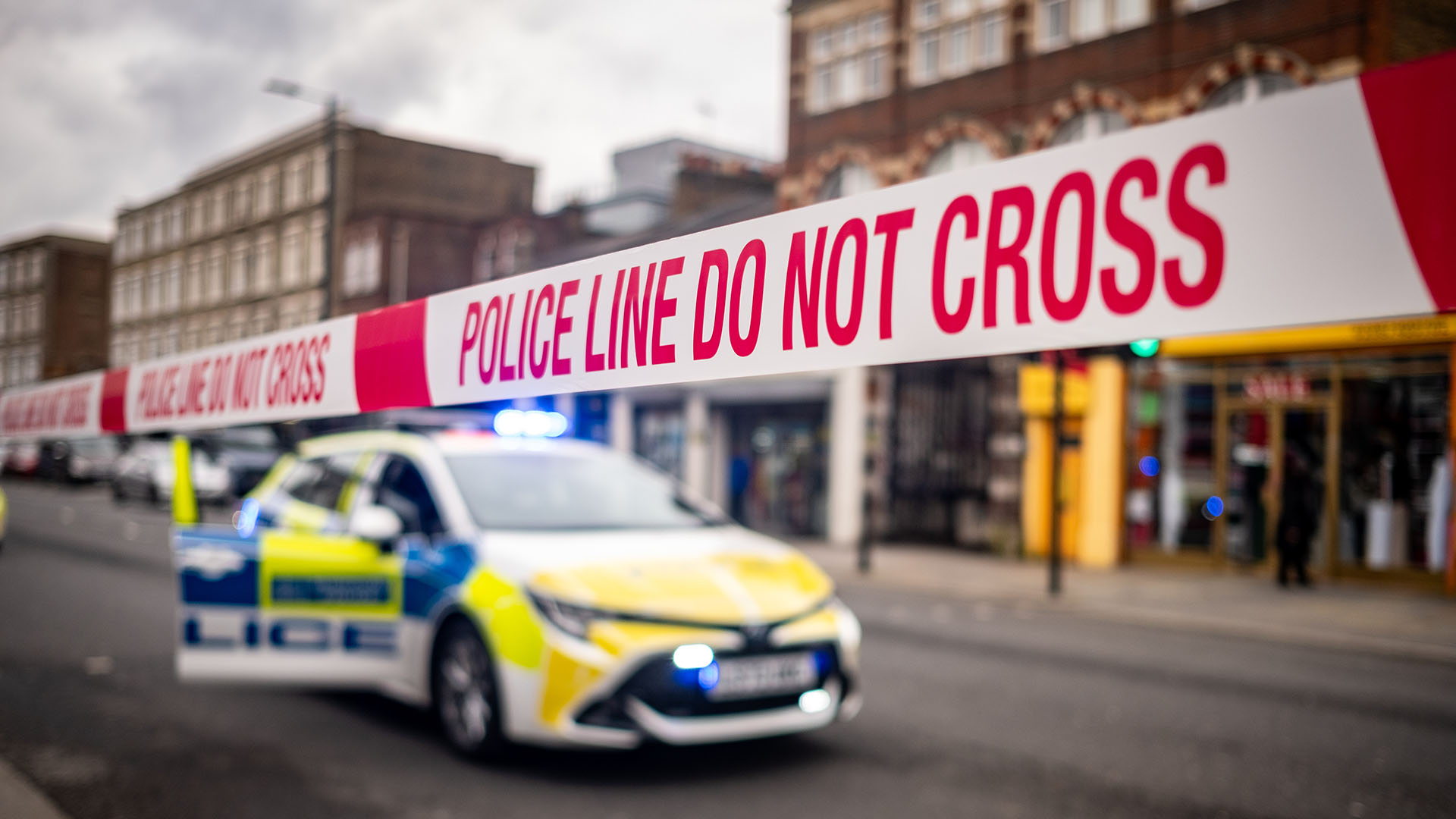 A police car behind police do not cross tape