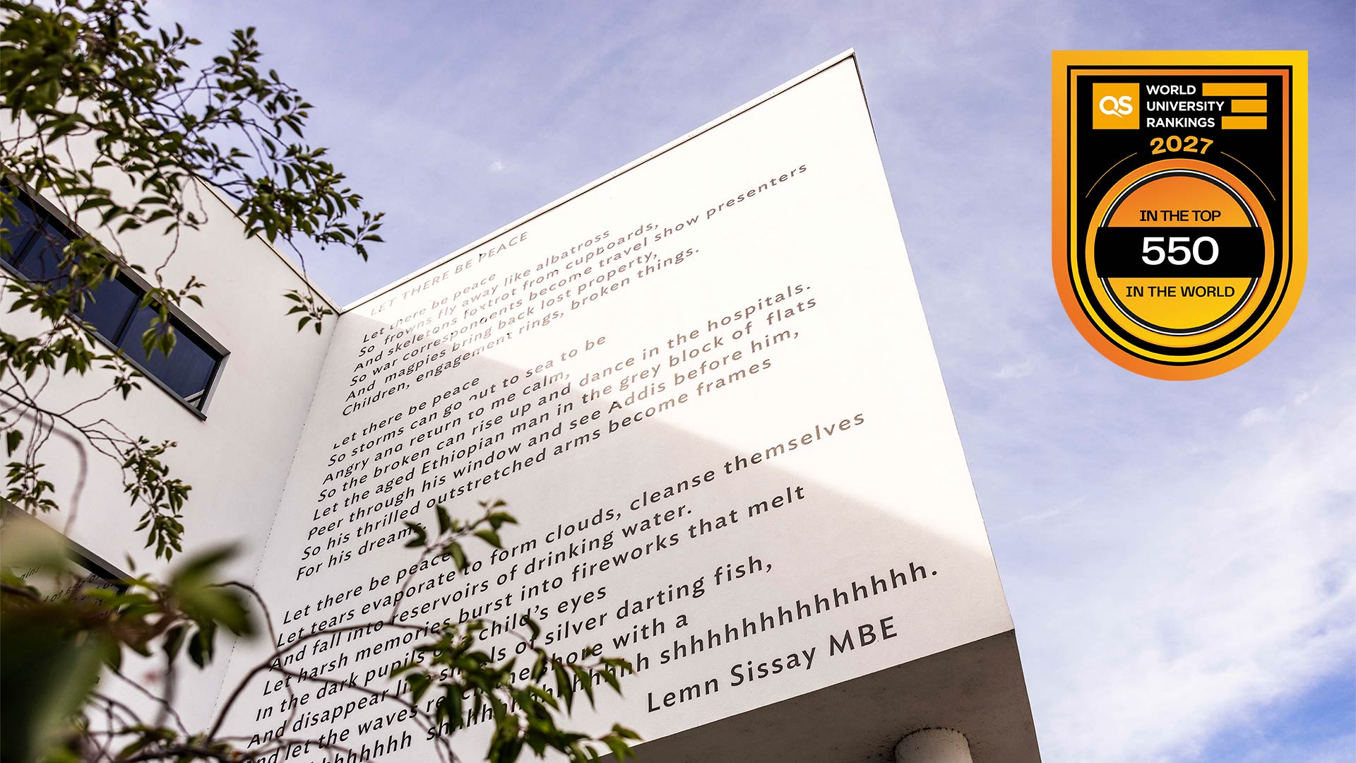 University building façade featuring “Let There Be Peace” poem by Lemn Sissay, viewed from below with tree branches and sky, alongside QS World University Rankings 2027 top 550 badge.