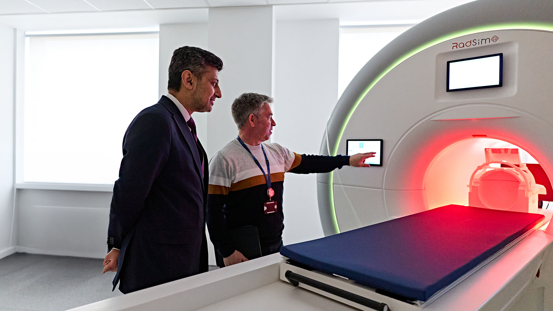 Two people look at an MRI scanner simulator