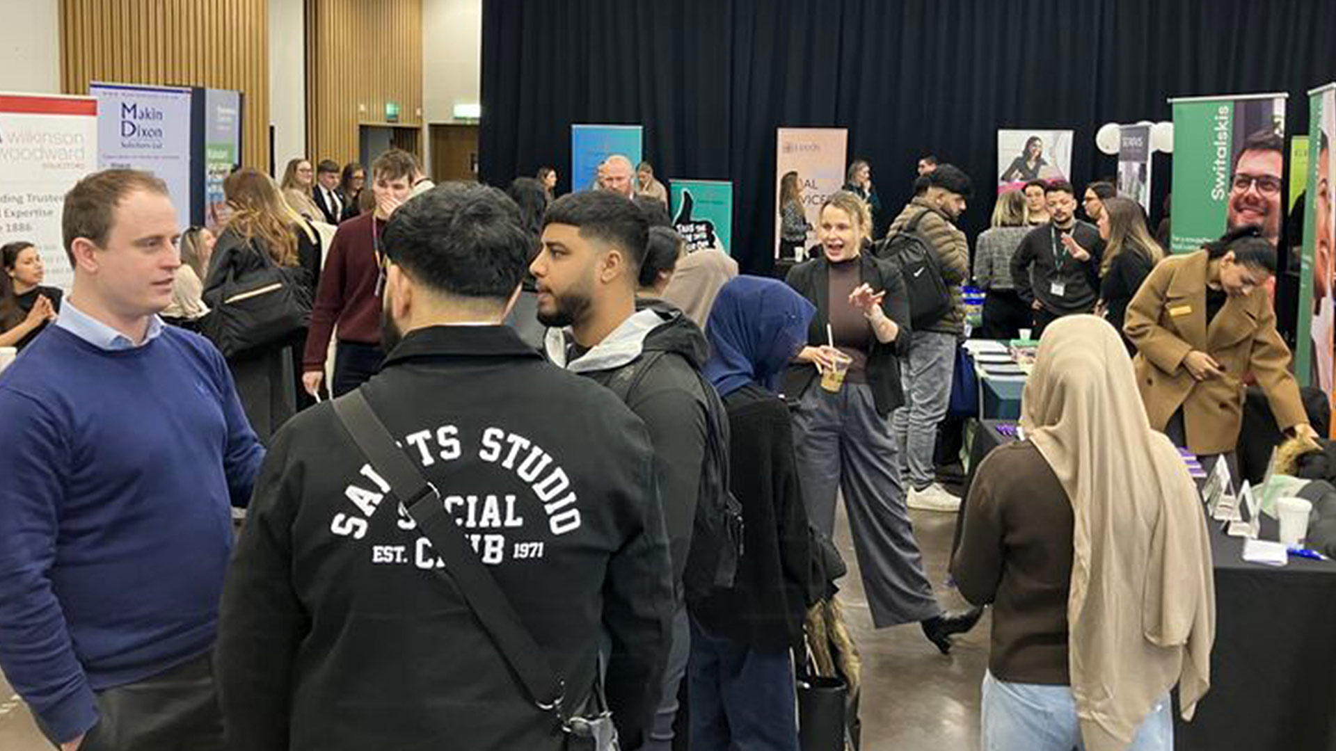 A group of male and female students milling about at a careers fair