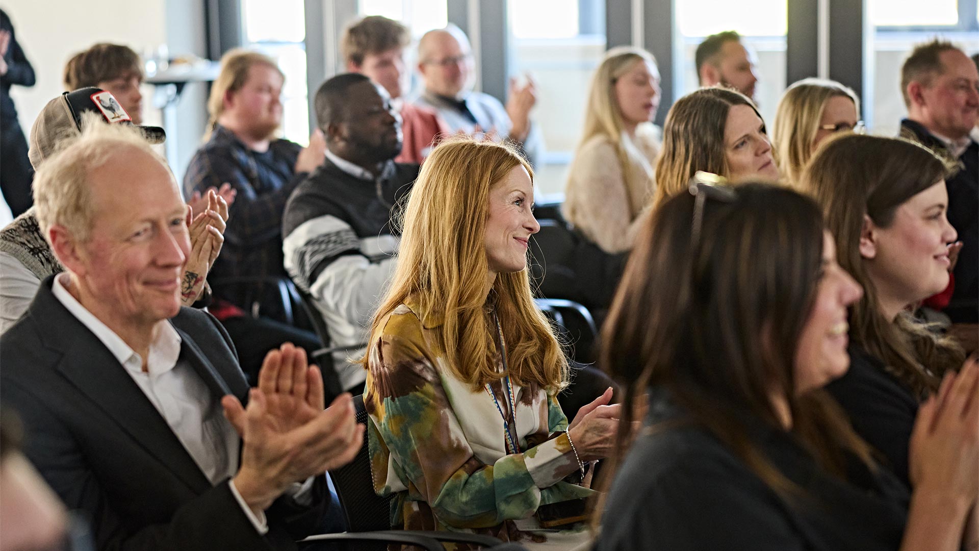 People sat in the audience, smiling and clapping