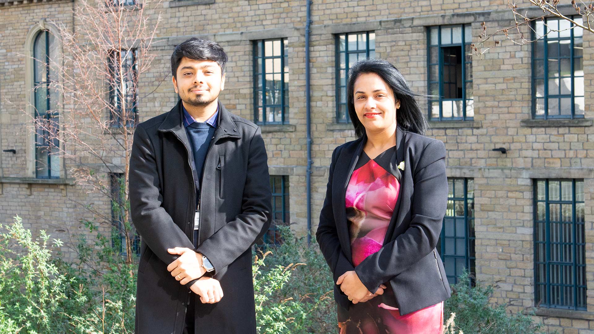 A man and a woman stood in front of a mill building