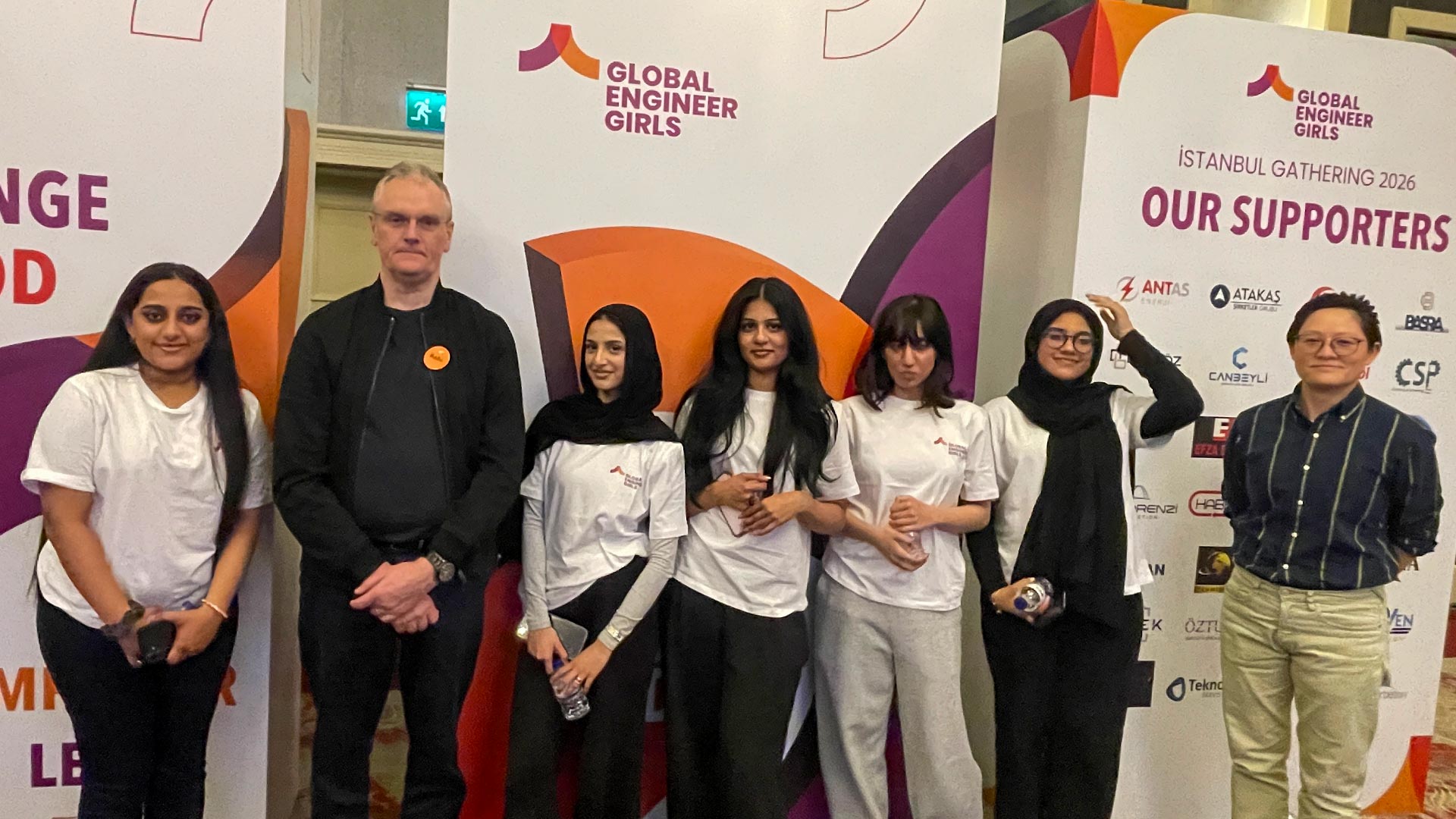 Small group standing beside Global Engineer Girls display boards at Istanbul Gathering 2026, with event branding and supporter logos visible.