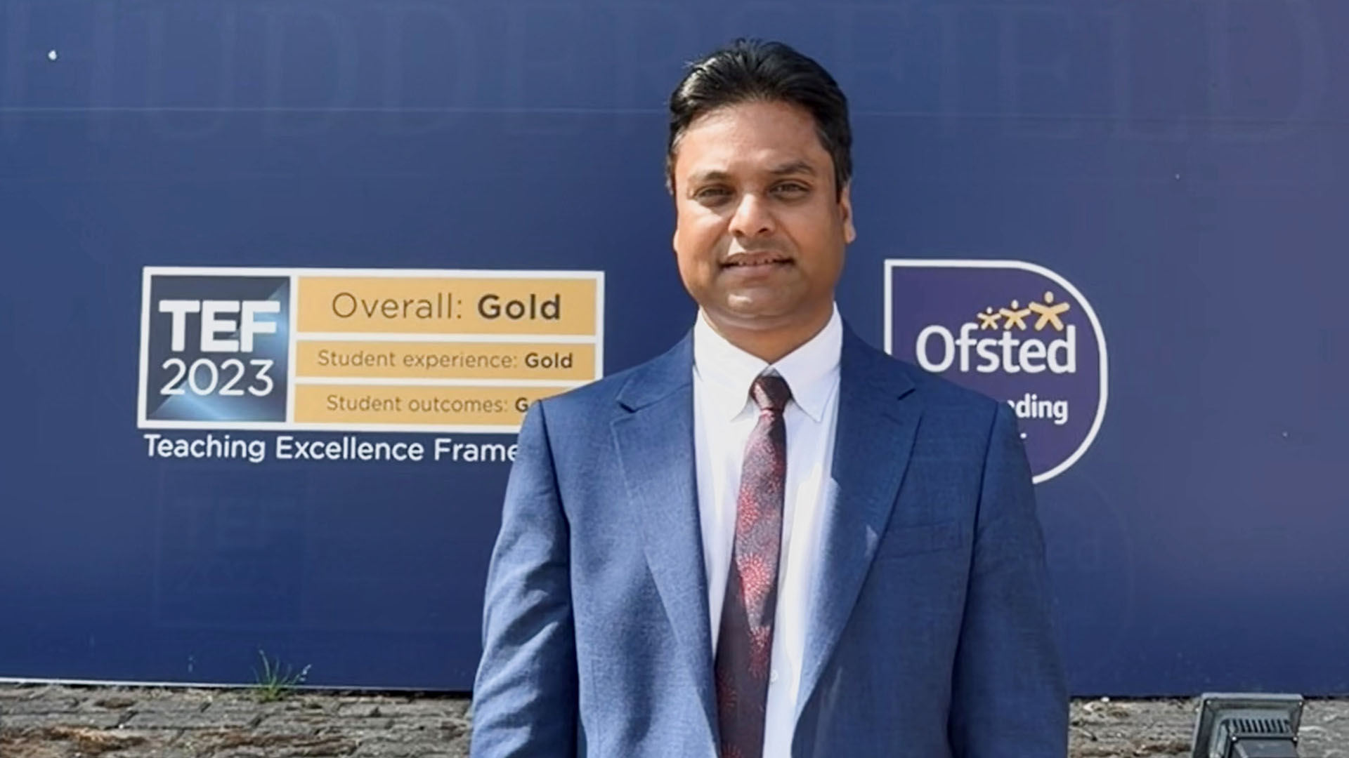 Rajeeb Kumar Sah in front of the University of Huddersfield signage.
