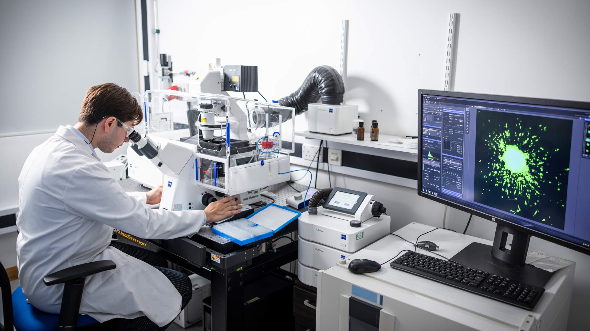 Student looking into digital microscope to analyse alongside data on screen