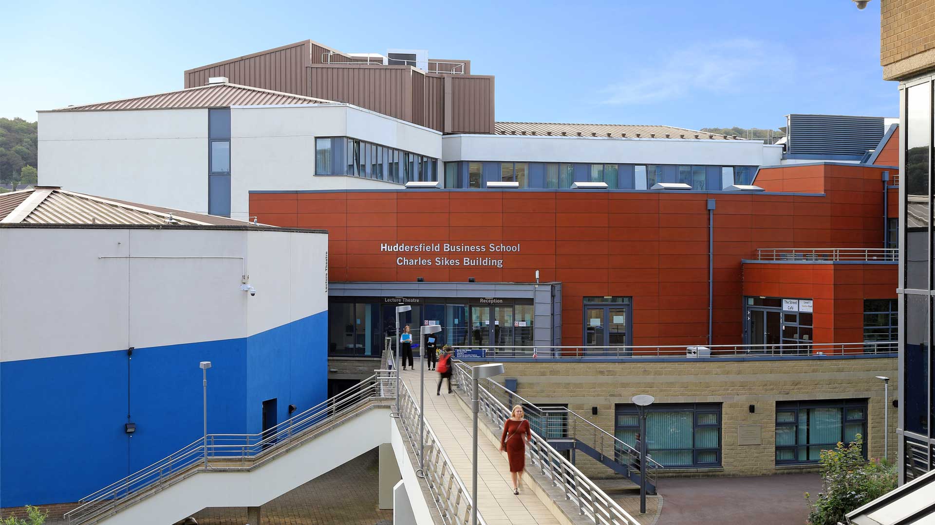 Shot of Huddersfield Business School with students walking across bridge in front