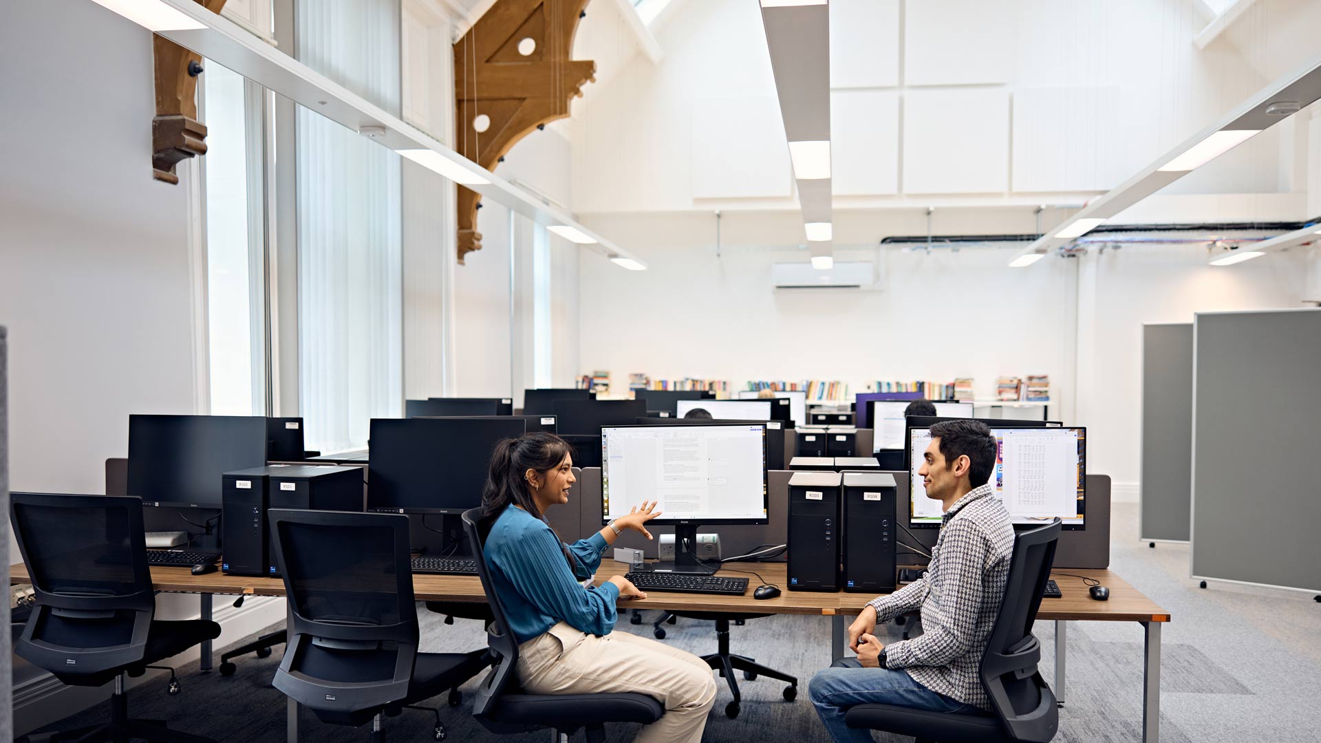 Student and tutor chatting about work on computer in new Doctoral College building