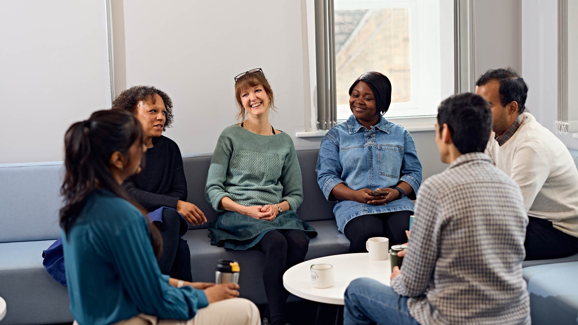 Staff in Doctoral College sitting and having group discussion with current researchers