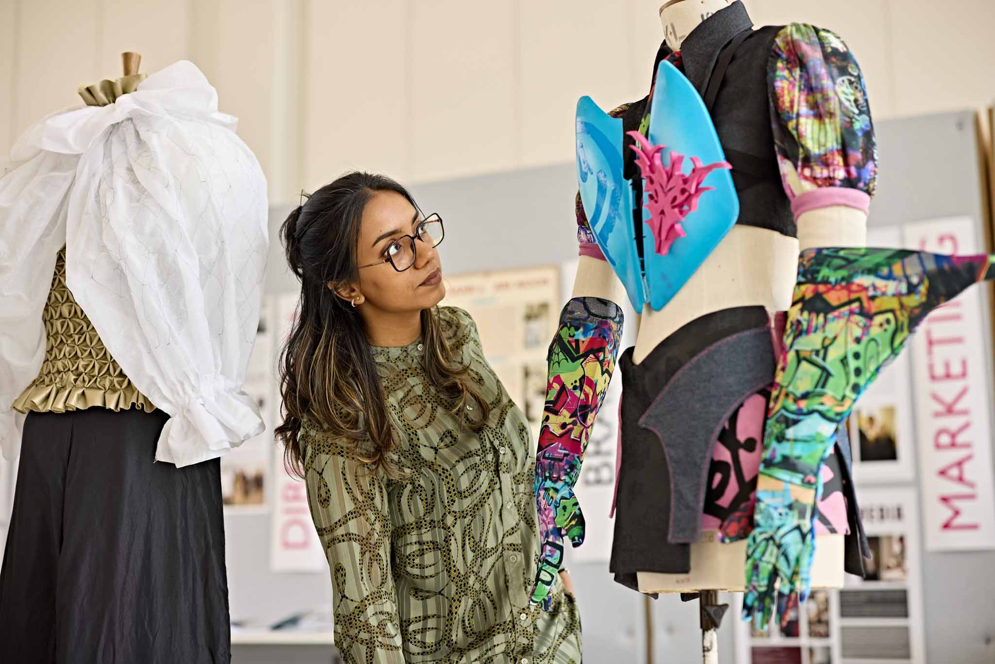 Fashion and textiles student looking at her clothes designs on a manekin