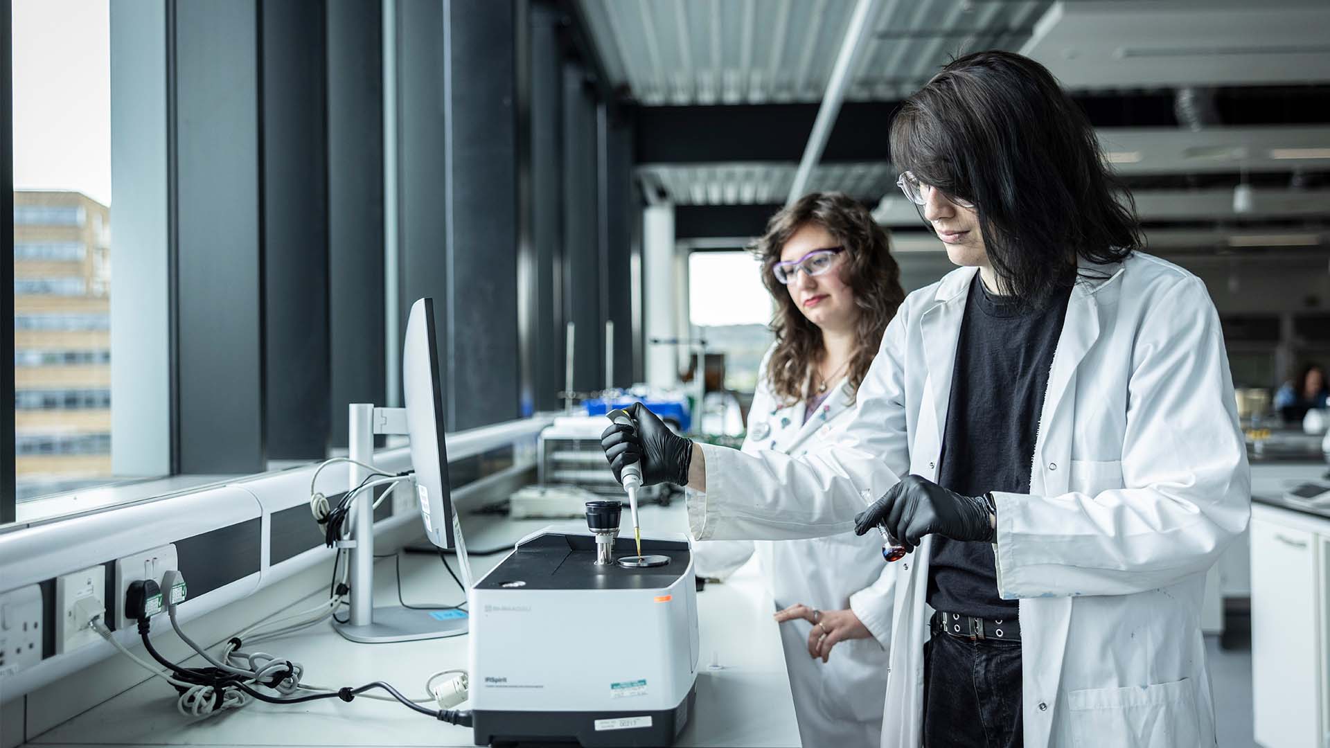 Two students in lab coats performing an experiment