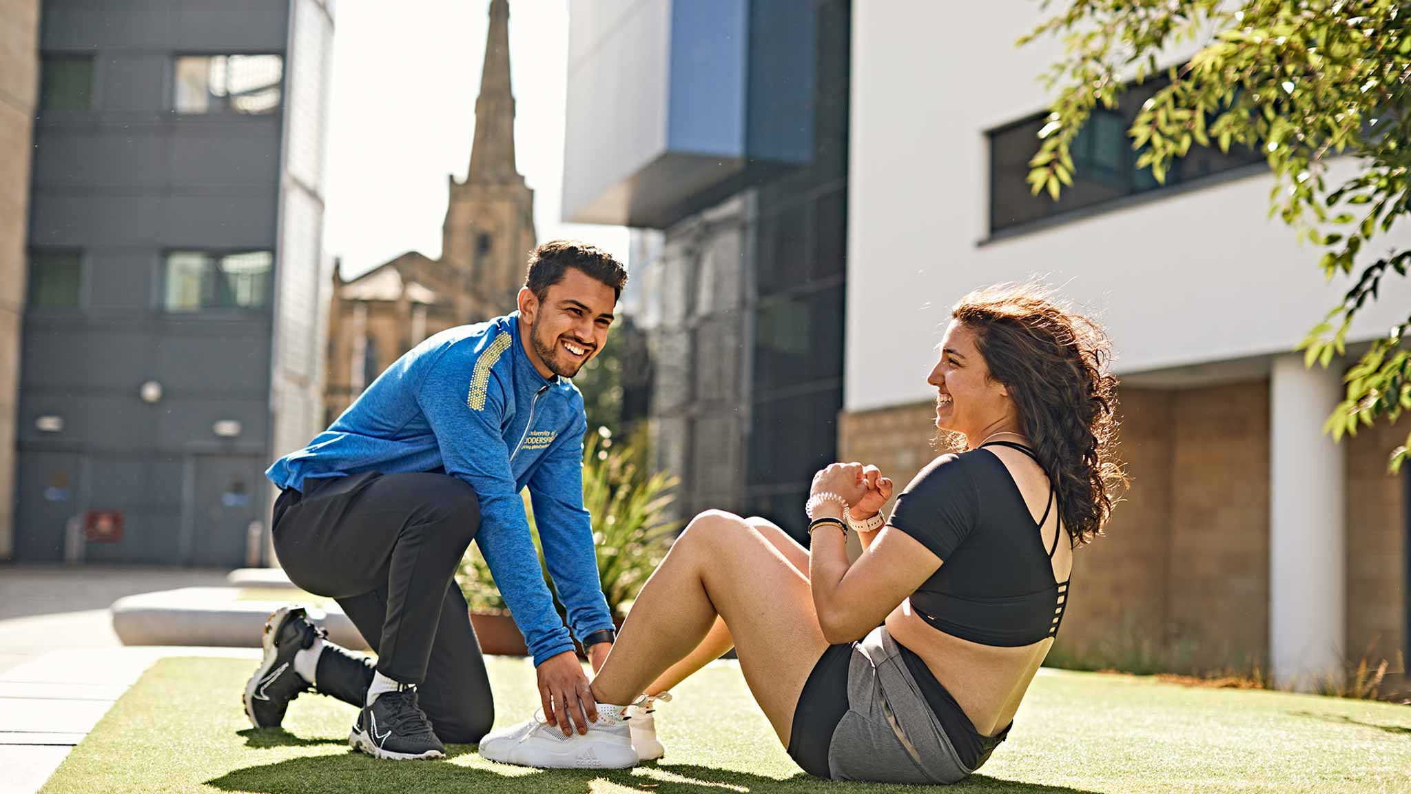 Two students exercising outside at our Huddersfield campus