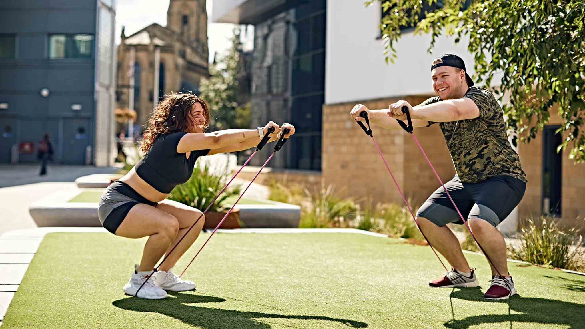 Two students exercising outside at our Huddersfield campus