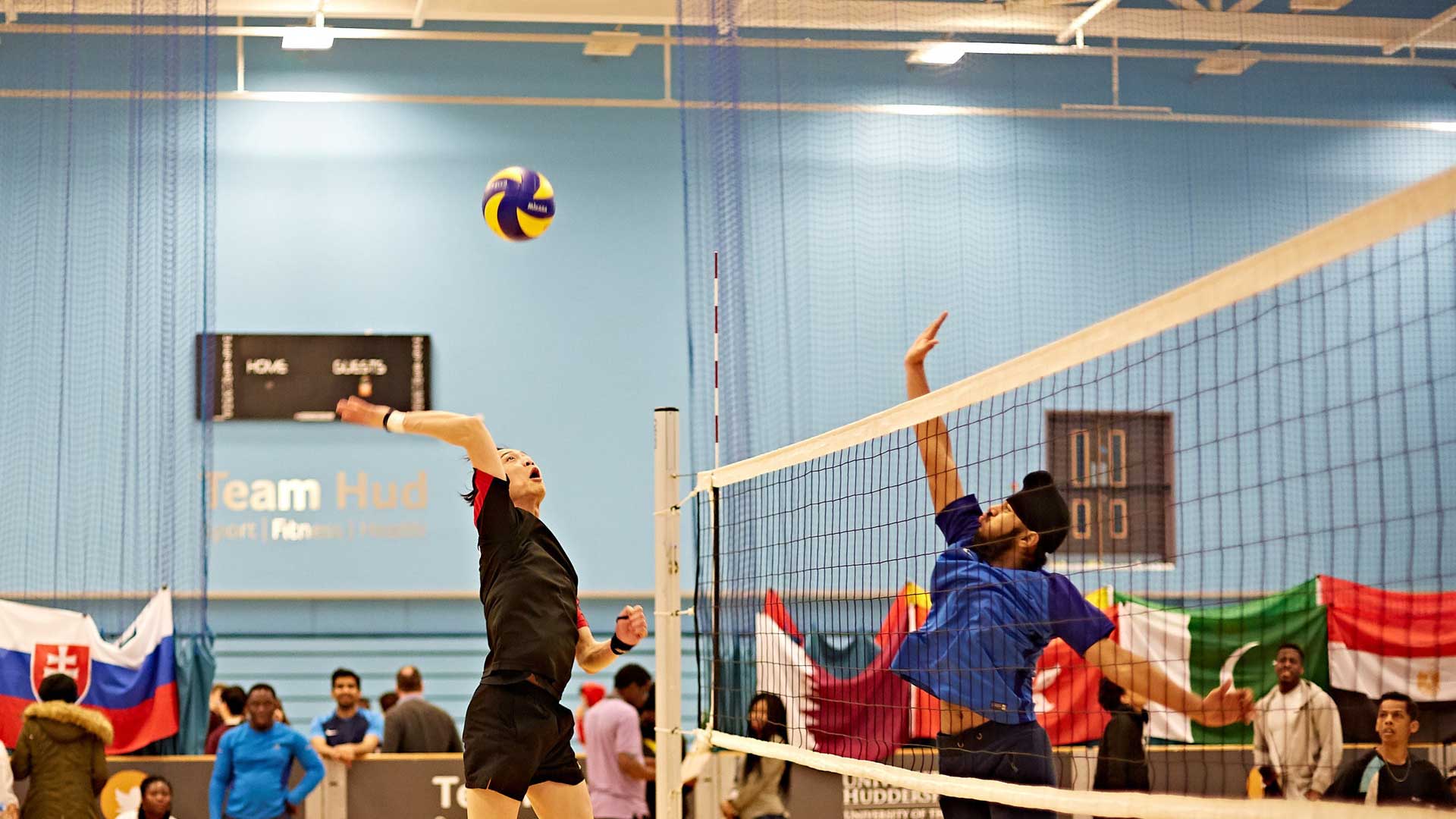 Picture of two students jumping up to hit a volleyball