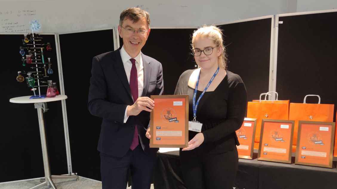 An award winner holds her award with Tim Thornton