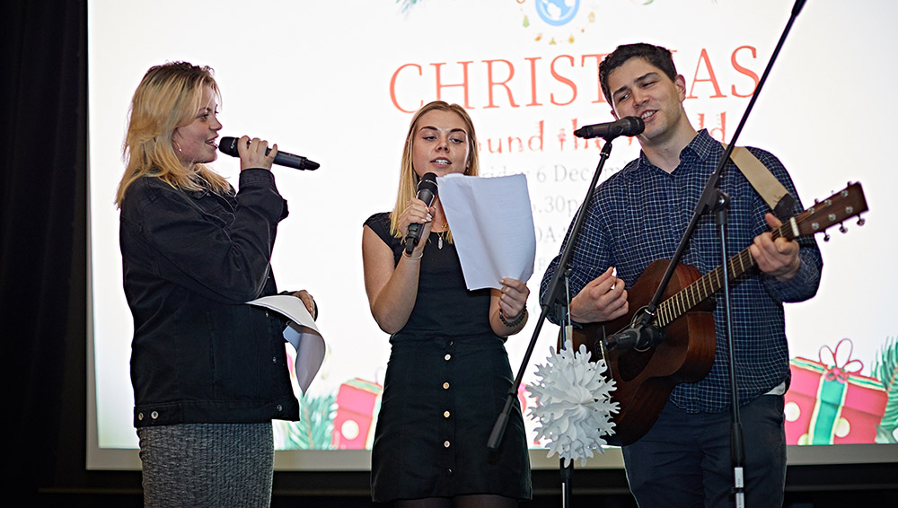 Three students doing a musical performance on stage at the Christmas Around the World event.