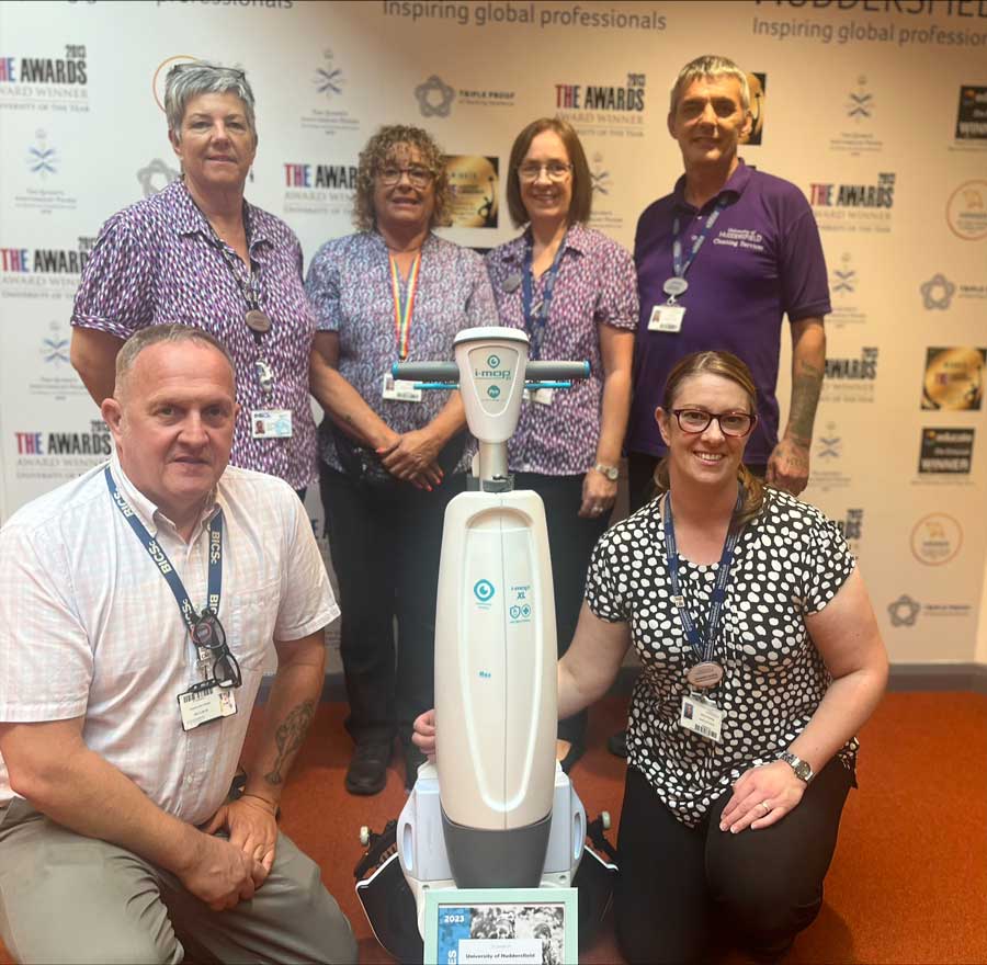 a picture of 6 members of the cleaning team posing with a mop