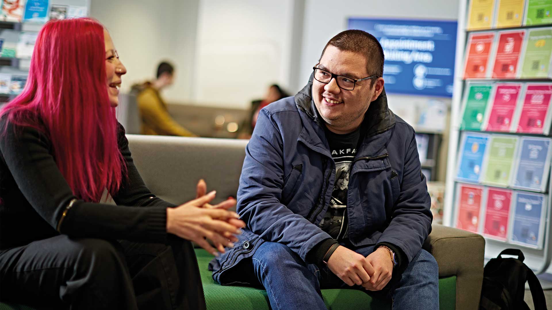 A disabled student chats to a support worker in the waiting area of Student Central