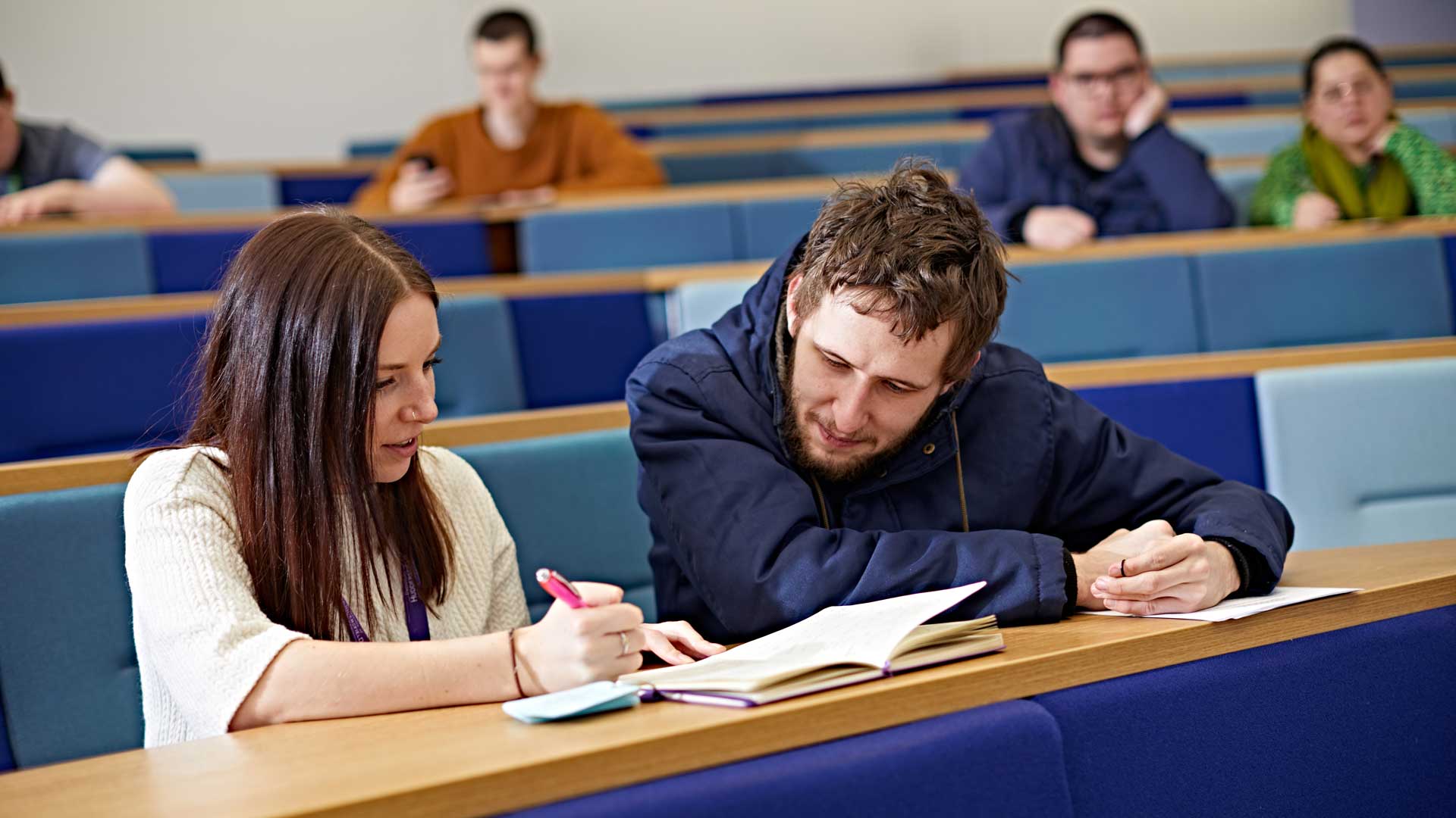 A male student working with a note taker in a lecture