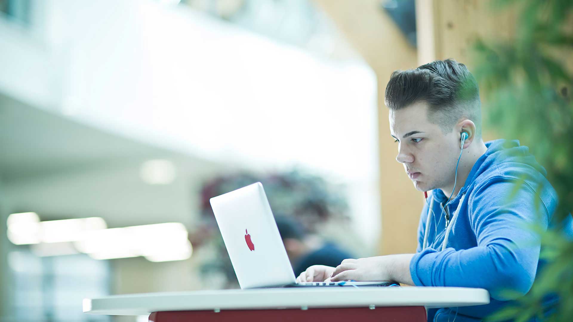 Huddersfield Business School student using a laptop in The Street in the Charles Sikes building