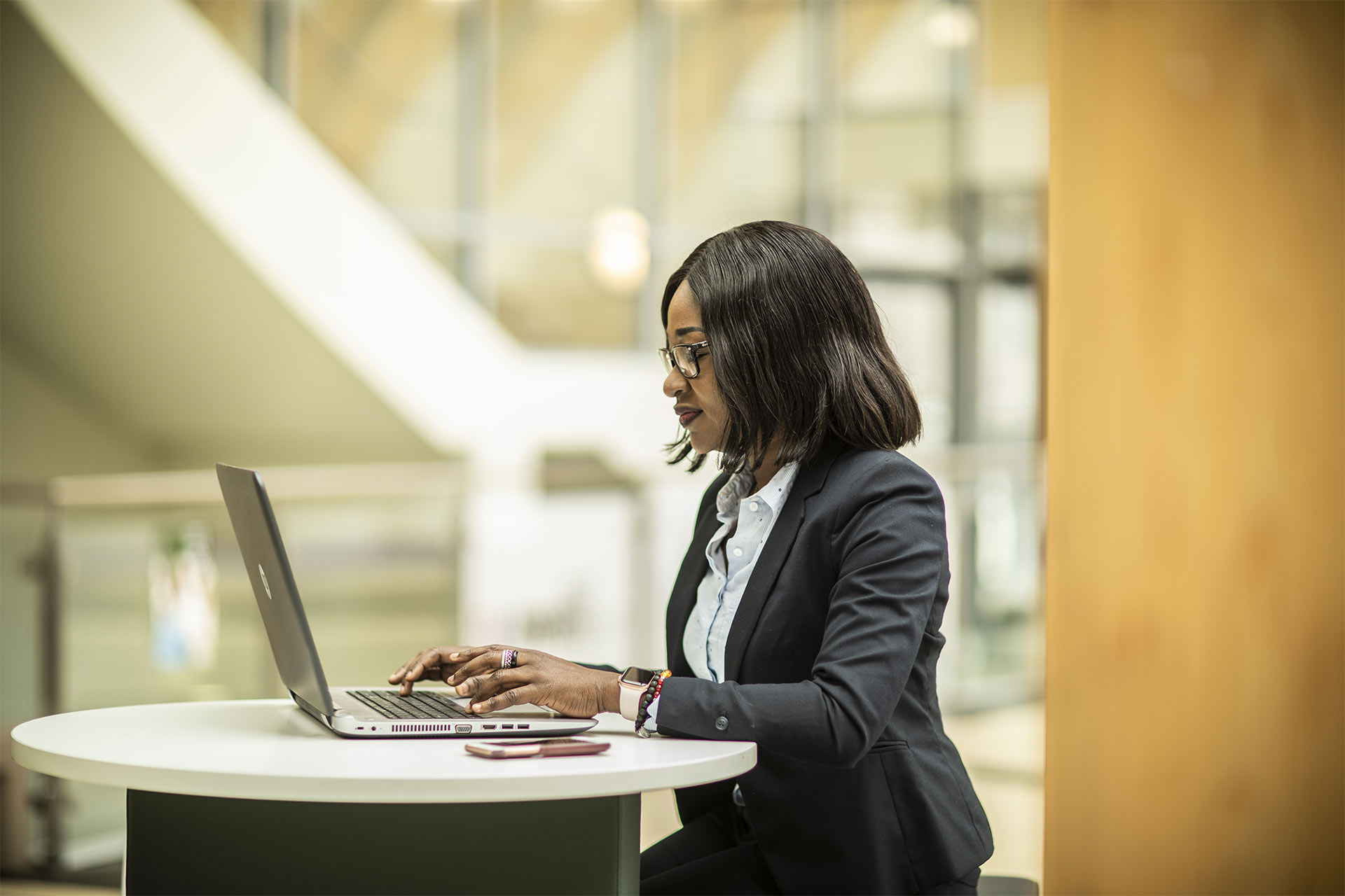 Postgraduate student using a laptop on a breakout table