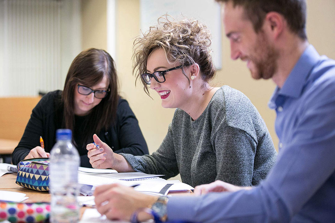 Postgraduate students studying at a desk in class