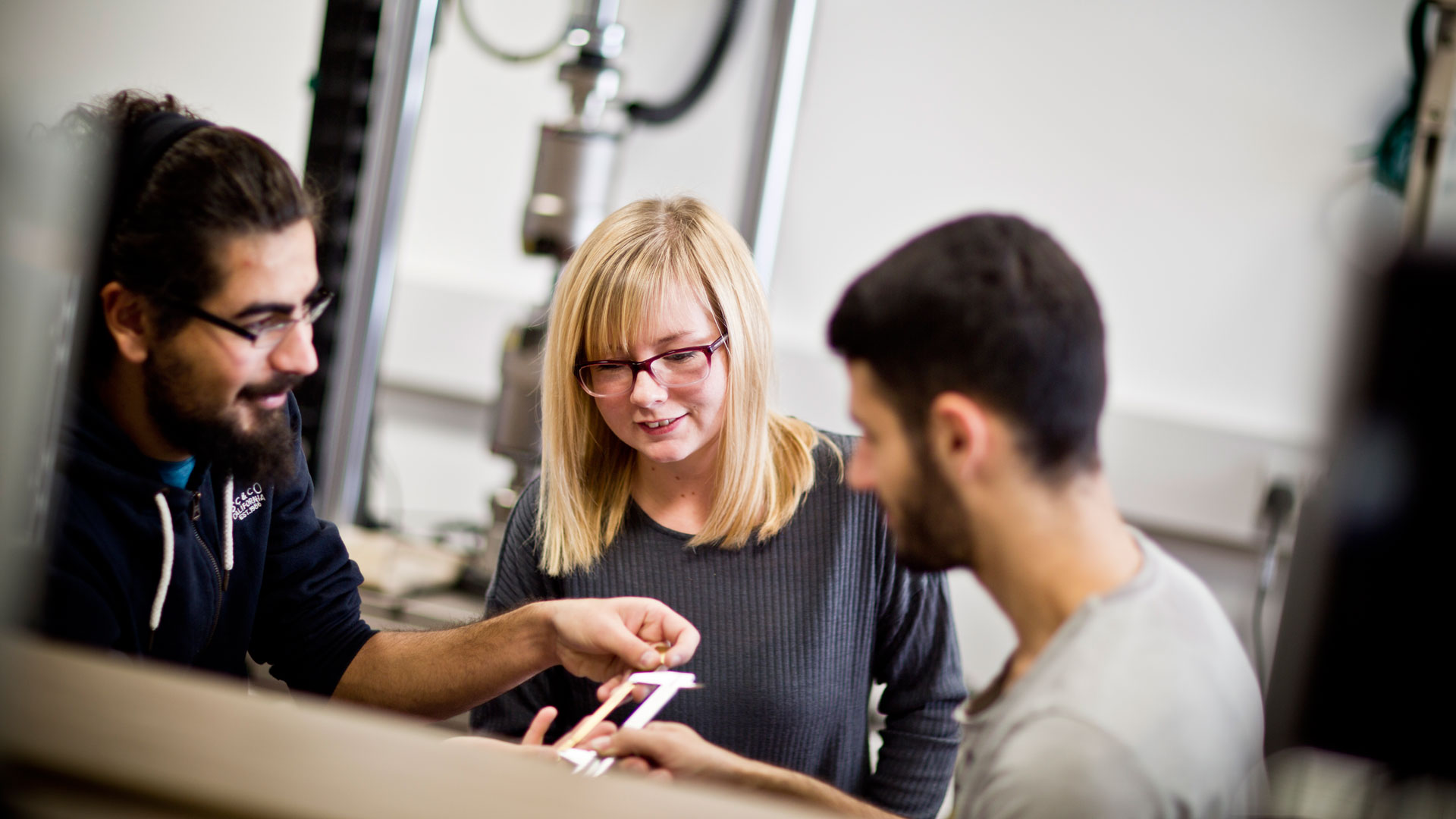 Three students sat at a table looking at research results