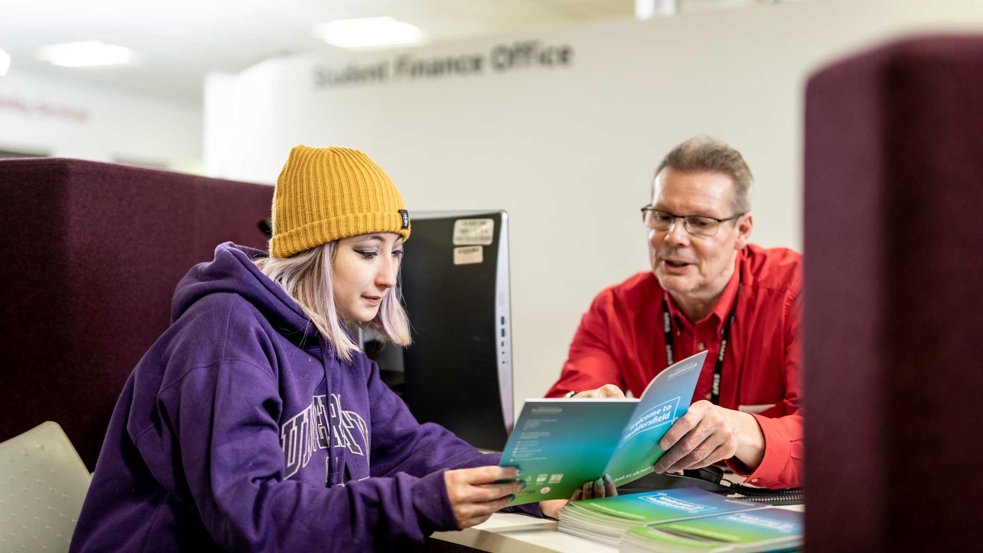 A student going through a finance booklet with staff from Student Finance