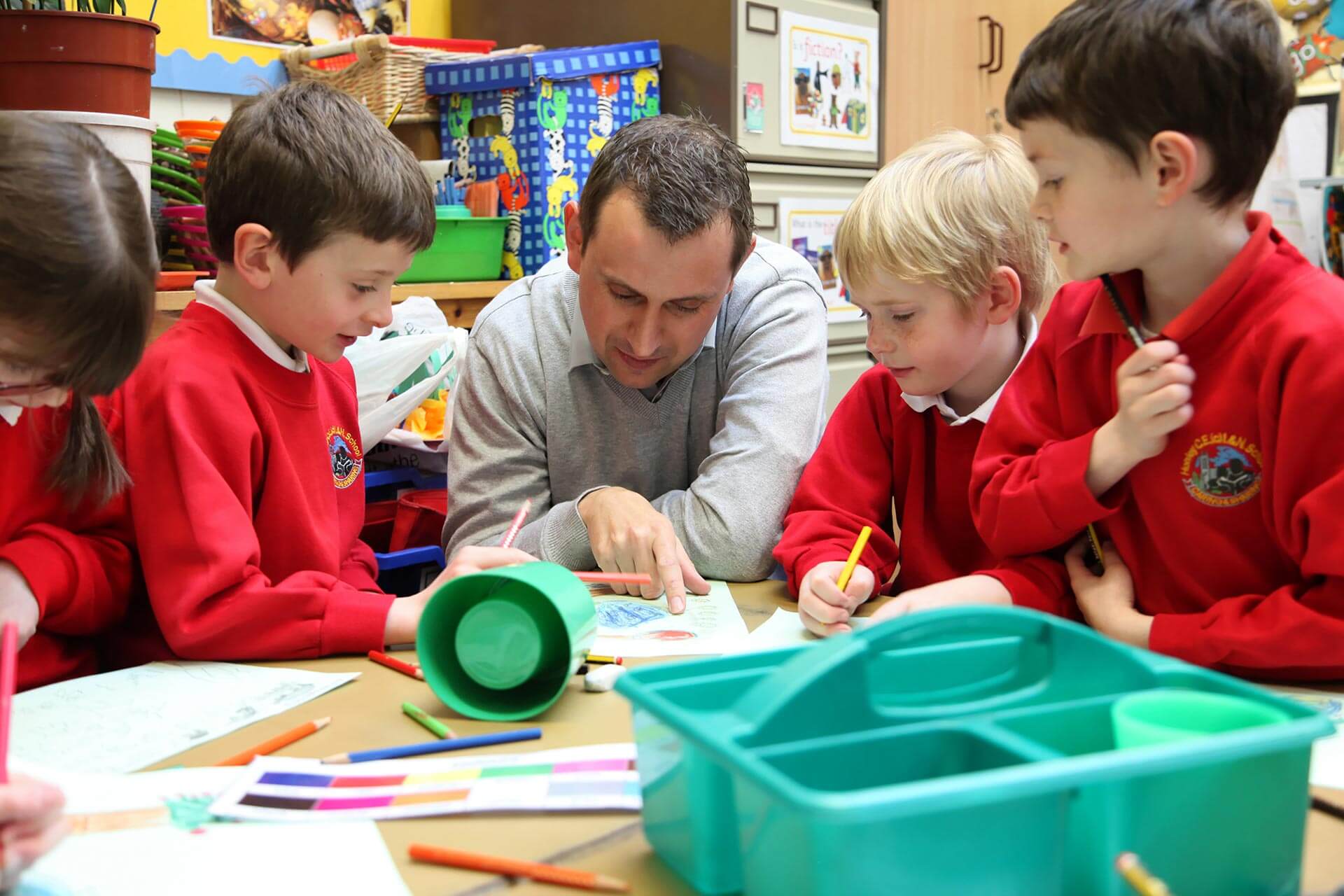 male primary teacher with school children around table