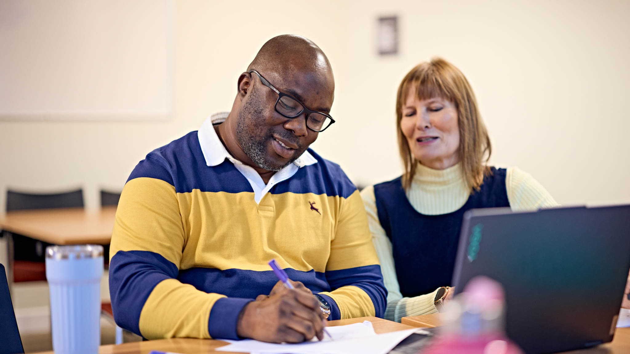 Trainee teacher working with adult learner, mentoring and coaching their work