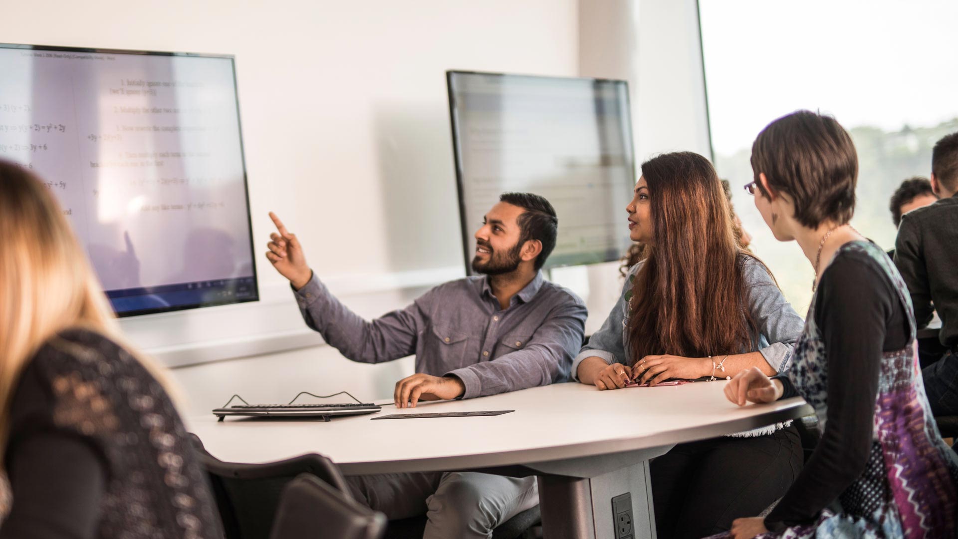 Students at a desk using computer presentations screens