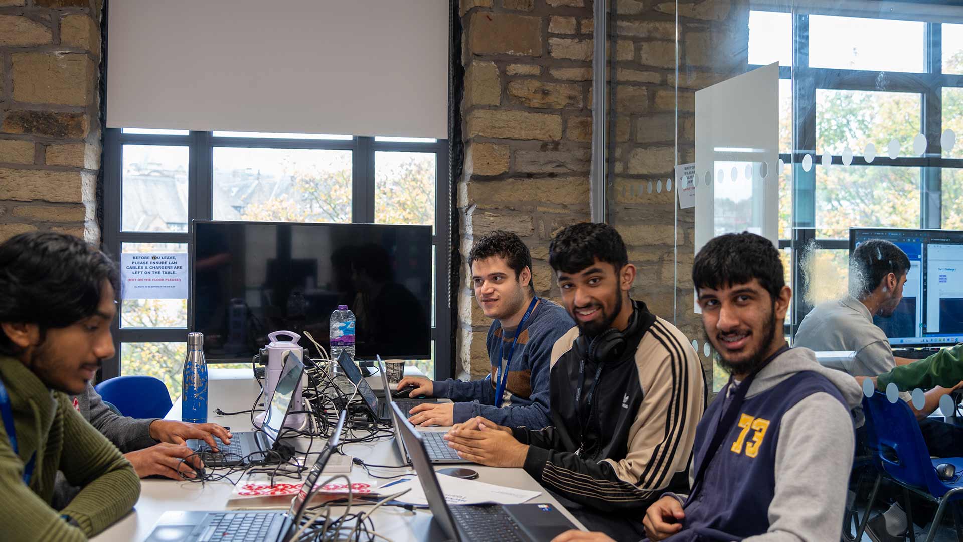 Edwin sat in a computer lab with some other students on the same bank of desks as him.
