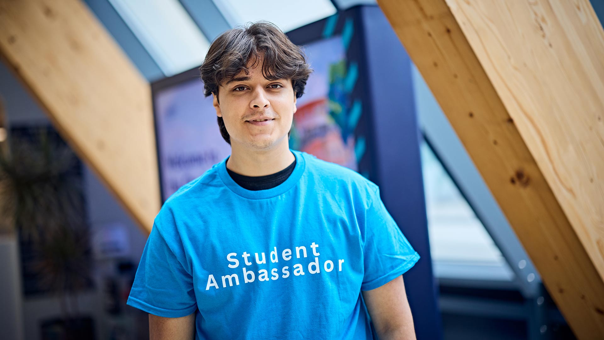 Above the waist shot of Mohammad wearing a blue University Student Ambassador t-shirt.