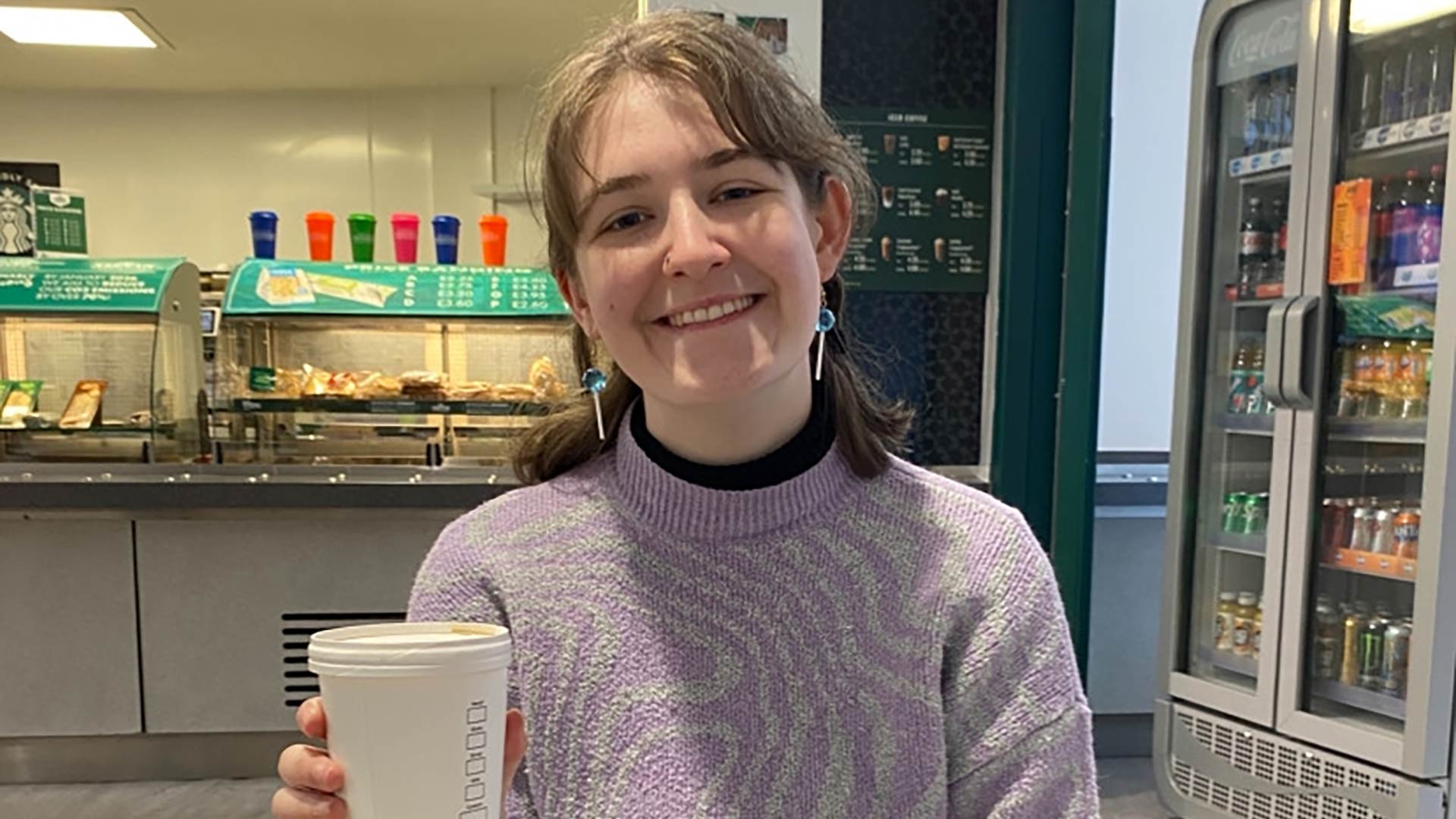 Sophie sat in a café on campus, holding a coffee cup.