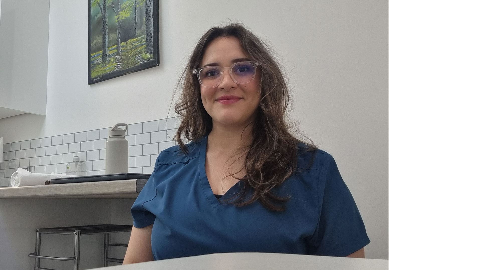 Syori Oates sitting at a table, smiling, in a Podiatry uniform.