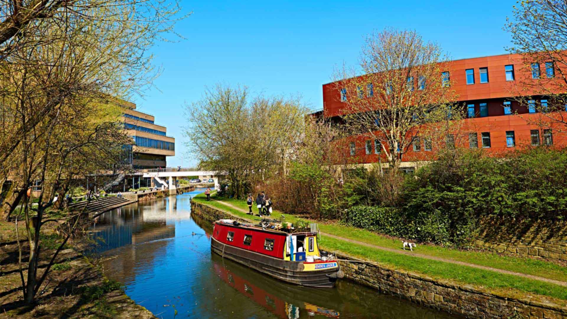 Picture of the canal by the business school. A red narrowboat is sat on the canal.