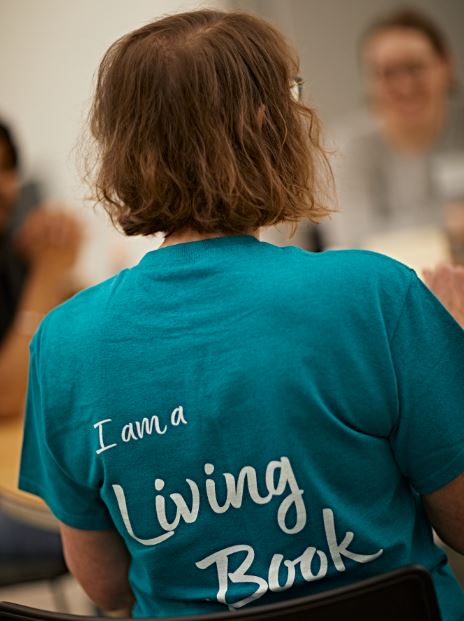 The back of a person wearing a t-shirt which says 'I am a living book'