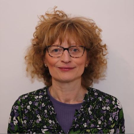 A woman smiling in front of a grey background