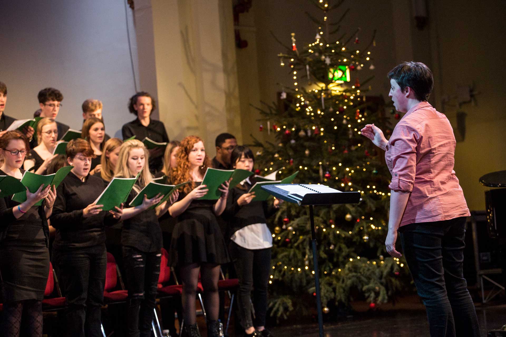 A choir is singing while being directed by an instructor